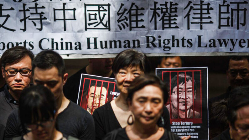 Retratos de los abogados chinos de derechos humanos detenidos Jian Tianyong (I) y Wang Quanzhang se ven mientras los activistas pro-democracia de Hong Kong observan una protesta silenciosa en apoyo de los abogados de derechos humanos en China frente a la Corte de Apelación Final en el distrito central de Hong Kong el 9 de julio de 2017. (Tengku Bahar/AFP/Getty Images)

