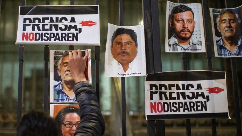 Fotografía de archivo de un periodista que pega una fotografía, durante una protesta el 14 de febrero de 2022, al exterior de la Secretaria de Gobernación (SG), en la Ciudad de México (México). EFE/Isaac Esquivel