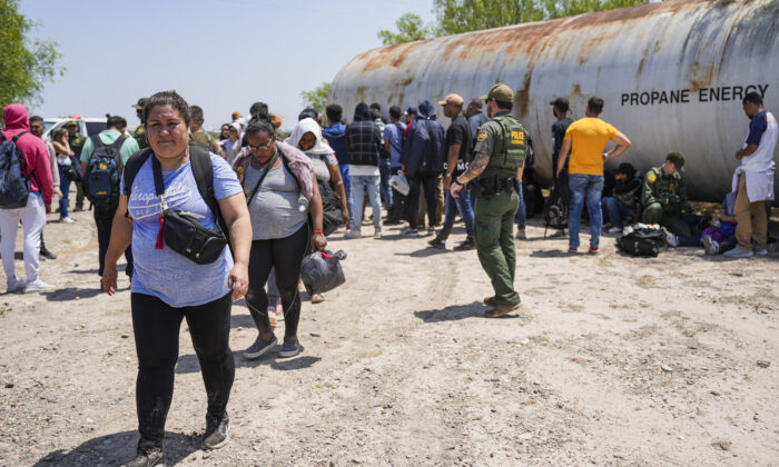 Un agente de la Patrulla Fronteriza organiza un gran grupo de inmigrantes ilegales cerca de Eagle Pass, Texas, el 20 de mayo de 2022. (Charlotte Cuthbertson/The Epoch Times)