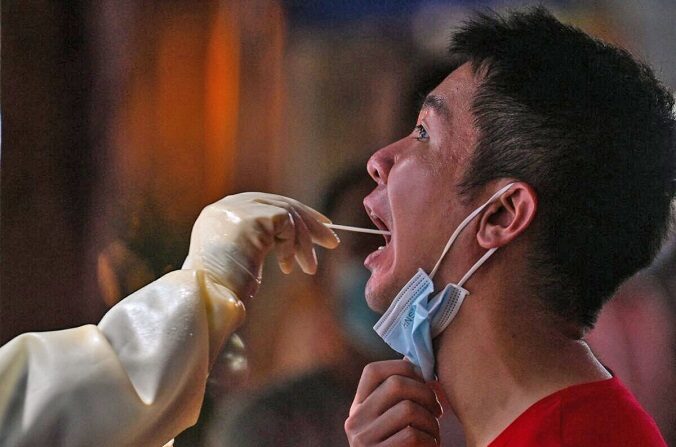 Un trabajador sanitario toma una muestra de un hombre para realizar una prueba por  COVID-19 en el distrito de Jing'an de Shanghái, China, el 31 de julio de 2022. (Hector Retamal/AFP vía Getty Images)
