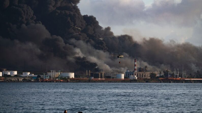 Un helicóptero de los bomberos recoge agua de la bahía de Matanzas para combatir un enorme incendio en un depósito de combustible provocado por un rayo en Matanzas, Cuba, el 8 de agosto de 2022. (Yamil Lage/AFP vía Getty Images)