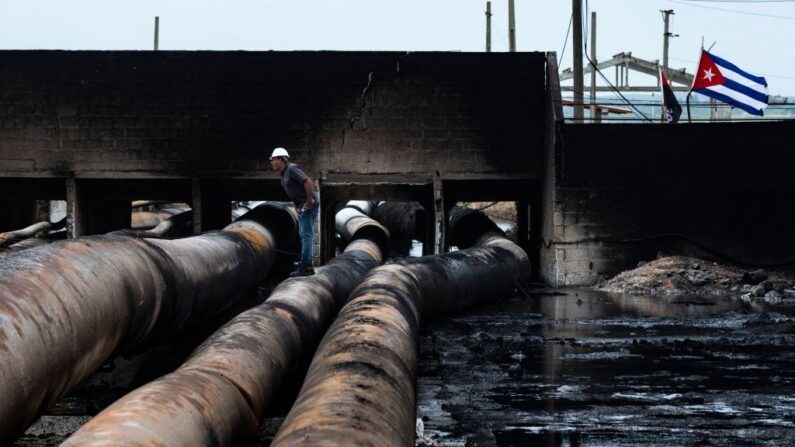 Un empleado de la compañía petrolera estatal Cupet inspecciona los daños en el depósito de combustible que estuvo envuelto en llamas durante cinco días después de que un rayo cayera en uno de sus tanques, en Matanzas, Cuba, el 10 de agosto de 2022. (Yamil Lage/AFP vía Getty Images)