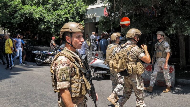 Soldados del ejército (delante) y fuerzas de seguridad (detrás) se reúnen frente a una sucursal del "Federal Bank" en Beirut, capital del Líbano, el 11 de agosto de 2022, cuando un hombre toma rehenes en el banco. (ANWAR AMRO/AFP vía Getty Images)