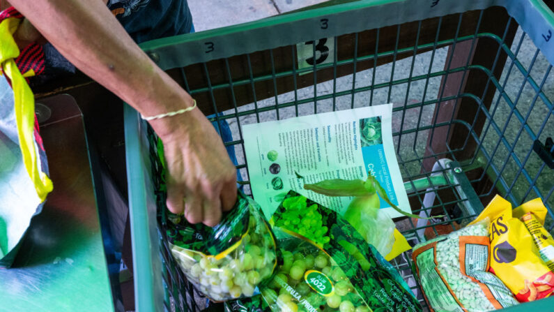 Un hombre llena sus bolsas con comida de la despensa de alimentos de Reaching Out Community Services el 11 de agosto de 2022 en el barrio de Brooklyn de la ciudad de Nueva York. (Spencer Platt/Getty Images)