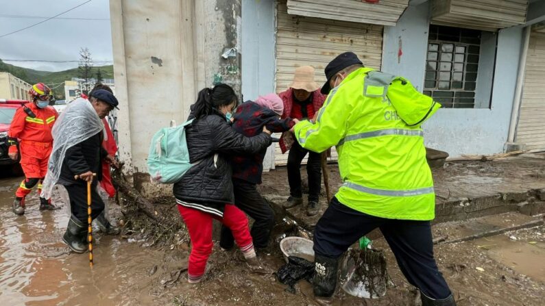 Esta foto tomada el 18 de agosto de 2022 muestra a los trabajadores de rescate evacuando a los residentes después de que una inundación repentina causada por un aguacero desencadenara deslizamientos de tierra en el condado de Datong, en la ciudad de Xining, en la provincia noroccidental china de Qinghai. (CNS/AFP vía Getty Images)