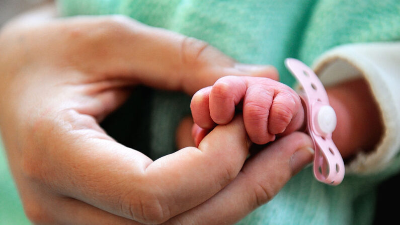 En una imagen ilustrativa, se ve un recién nacido toma el dedo de su madre. (Philippe Huguen/AFP vía Getty Images)