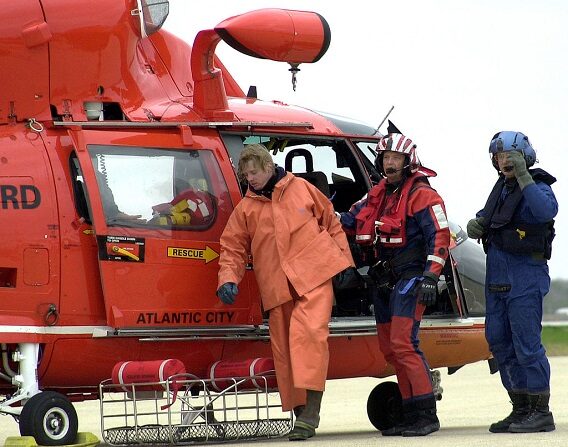 El nadador de rescate de la Guardia Costera de EE.UU. Dave Beacham (C) y el mecánico de vuelo Mark Ariza ayudan a un miembro de la tripulación del barco pesquero Kathy Ann a descender de un helicóptero tras un rescate en alta mar el 17 de abril de 2003 a unas 35 millas de la costa de Barnegat, Nueva Jersey. (Bill Barry/U.S. Coast Guard/Getty Images)
