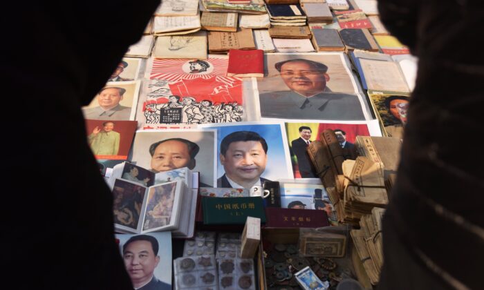 Los clientes miran los carteles del presidente chino Xi Jinping (C), y del difunto líder comunista Mao Zedong (centro iz y arriba de), en un mercado en Beijing el 26 de febrero de 2018. (Greg Baker/AFP vía Getty Images)