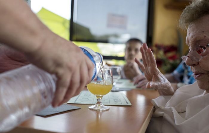 Una enfermera sirve una bebida a una mujer en una residencia para personas mayores dependientes (EHPAD) en Lyon el 2 de julio de 2015 mientras una abrasadora ola de calor recorre Europa. (ROMAIN LAFABREGUE/AFP vía Getty Images)