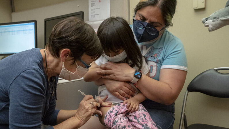 Una niña de 2 años recibe su primera dosis de la vacuna COVID-19 de Pfizer de manos de una enfermera mientras es sostenida por su madre, en el Centro Médico UW - Roosevelt en Seattle, Washington, el 21 de junio de 2022. (David Ryder/Getty Images)
