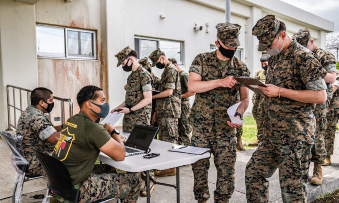Infantes de marina de EE.UU. registran sus datos mientras hacen fila para recibir la vacuna de Moderna contra el coronavirus, en Kin, Japón, el 28 de abril de 2021. (Carl Court/Getty Images)
