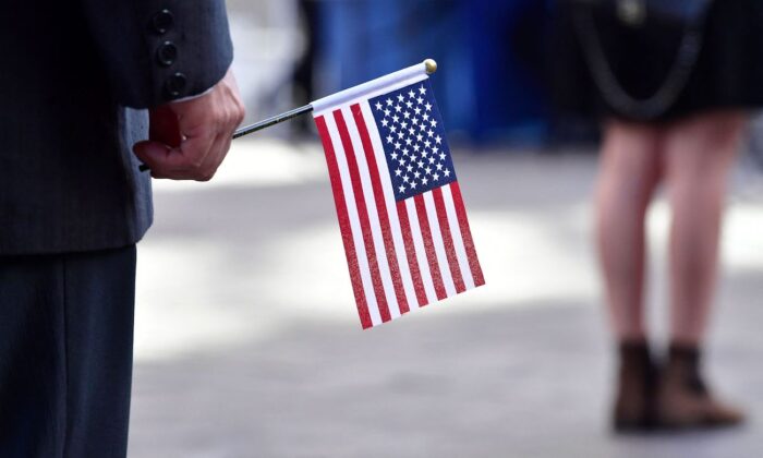 Personas sostienen banderas estadounidenses mientras asisten a su ceremonia de juramento de naturalización para obtener la ciudadanía estadounidense en Los Ángeles, California, el 25 de mayo de 2022. (FREDERIC J. BROWN/AFP vía Getty Images)