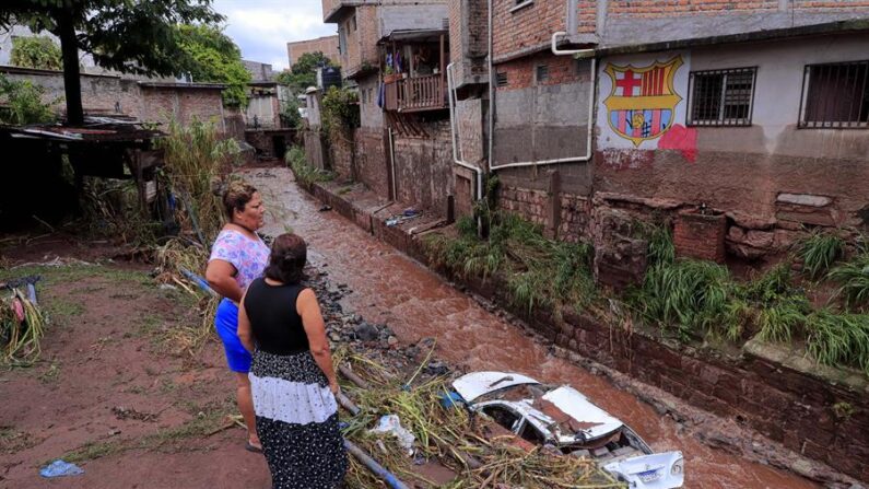 Imagen de archivo de dos mujeres que observan un auto arrastrado debido al desbordamiento de una quebrada en Tegucigalpa (Honduras). EFE/ Gustavo Amador