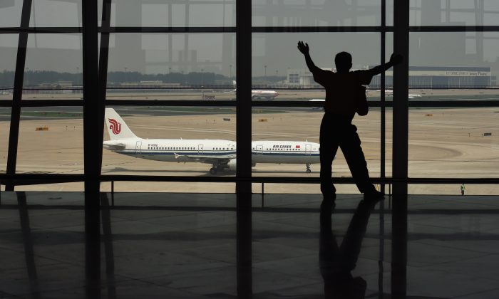 Un hombre mira un avión a través de una ventana en el aeropuerto internacional de Beijing. (Greg Baker/AFP/Getty Images)
