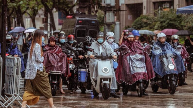 La gente monta scooters durante un día lluvioso cuando se espera que el tifón Muifa toque tierra, en Shanghai, China, el 14 de septiembre de 2022. EFE/Alex Plavevski