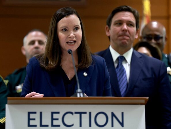 El gobernador de Florida, Ron DeSantis, escucha mientras la fiscal general de Florida, Ashley Moody, habla durante una conferencia de prensa en el tribunal del condado de Broward en Fort Lauderdale, Florida, el 18 de agosto de 2022. (Joe Raedle/Getty Images)
