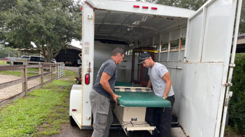 Carl Mottler (I) y el empleado Jordan Carlson descargan equipo médico en el rancho de Mottler en Punta Gorda, Florida, el 27 de septiembre de 2022. (Cortesía de Lisa Mottler)
