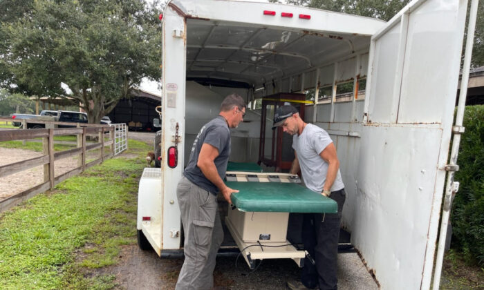 Carl Mottler (iz) y el empleado Jordan Carlson descarga equipo médico en el rancho de Mottler en Punta Gorda, Florida, el 27 de septiembre de 2022. (Cortesía de Lisa Mottler)