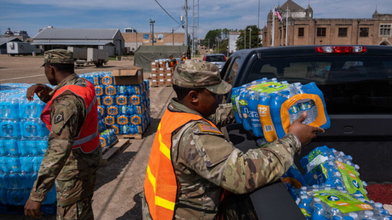 Un miembro de la Guardia Nacional coloca una caja de agua en la parte trasera de un coche en el State Fair Grounds en Jackson, Mississippi, el 2 de septiembre de 2022. (Seth Herald/AFP vía Getty Images)