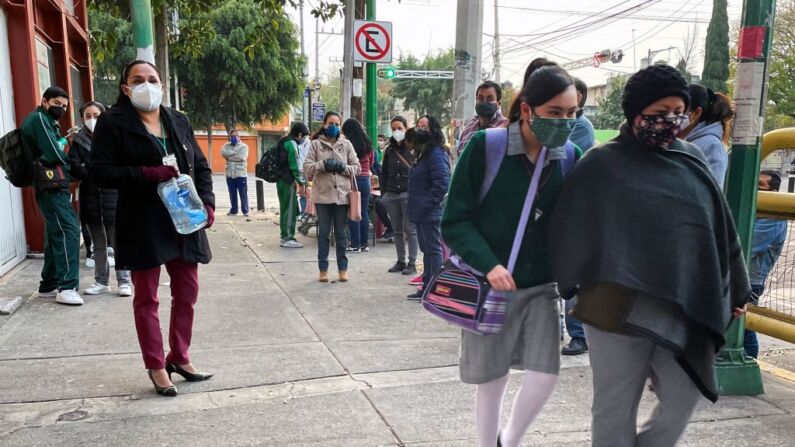 Una adolescente acompañada de su mamá, llega a la escuela en la Ciudad de México, el 10 de enero de 2022. (ALFREDO ESTRELLA/AFP vía Getty Images)