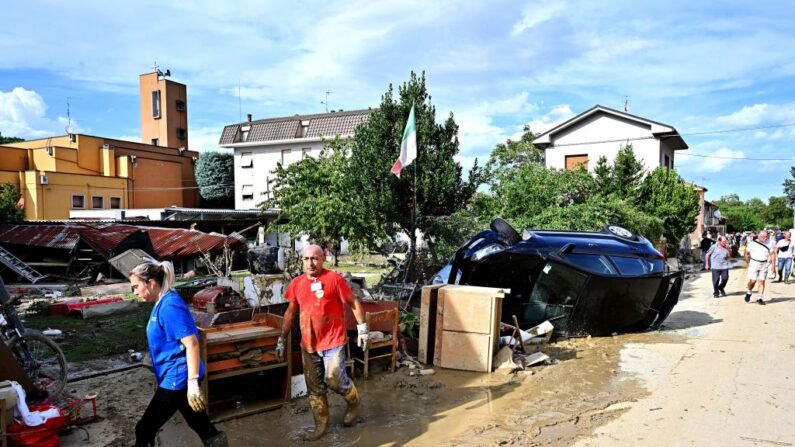 Unas personas limpian una calle fuera de las casas inundadas tras una bomba de lluvia nocturna en Pianello di Ostra, provincia italiana de Ancona, el 16 de septiembre de 2022. (Alberto Pizzoli/AFP vía Getty Images)
