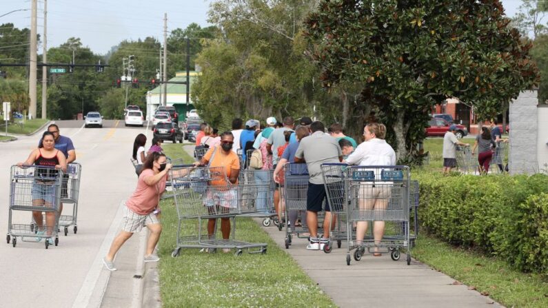 Los compradores se unen a una línea que se extiende más allá del estacionamiento fuera de un almacén de venta al por menor como la gente se apresura a prepararse para la tormenta tropical Ian, en Kissimmee, Florida, el 25 de septiembre de 2022. (GREGG NEWTON/AFP vía Getty Images)