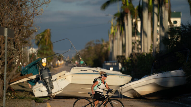 Mujer camina con su bicicleta por delante de  barcos que bloquean la calle después del huracán Ian el 29 de septiembre de 2022 en Bonita Springs, Florida. (Sean Rayford/Getty Images)