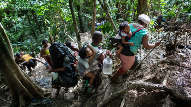 Familias de inmigrantes ilegales de Haití suben un sendero de montaña empinado cerca de la frontera con Panamá en el segundo día de su caminata, el 19 de octubre de 2021 a través del Tapón del Darién, Colombia. (John Moore/Getty Images)