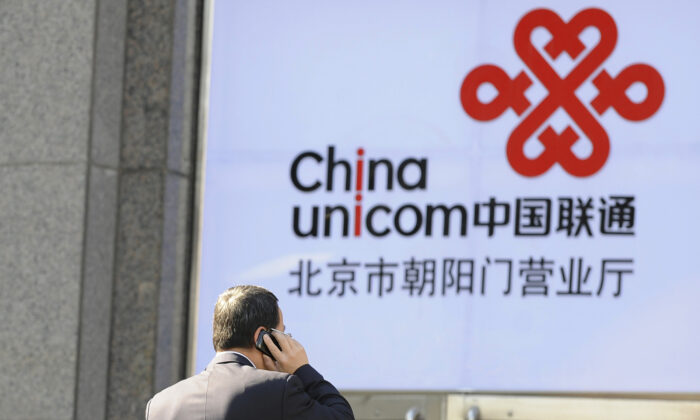 Un oficinista habla por un teléfono móvil frente a un logotipo de China Unicom, el socio de Apple en China, en Beijing, el 5 de enero de 2012. (Liu Jin/AFP vía Getty Images)
