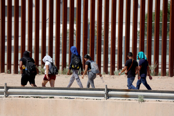 Migrantes caminan a lo largo de la valla fronteriza de EE.UU. para entregarse a la Patrulla Fronteriza de EE.UU. después de cruzar el Río Grande desde México, en El Paso, Texas, el 21 de septiembre de 2022. (Joe Raedle/Getty Images)
