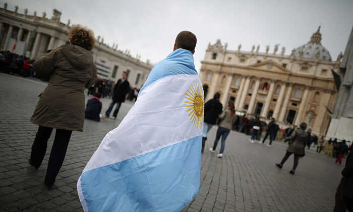 Un joven camina en la Plaza de San Pedro envuelto en la bandera de Argentina antes de la primera bendición del Ángelus del Papa Francisco, en la Ciudad del Vaticano, el 17 de marzo de 2013. (Peter Macdiarmid/Getty Images)

