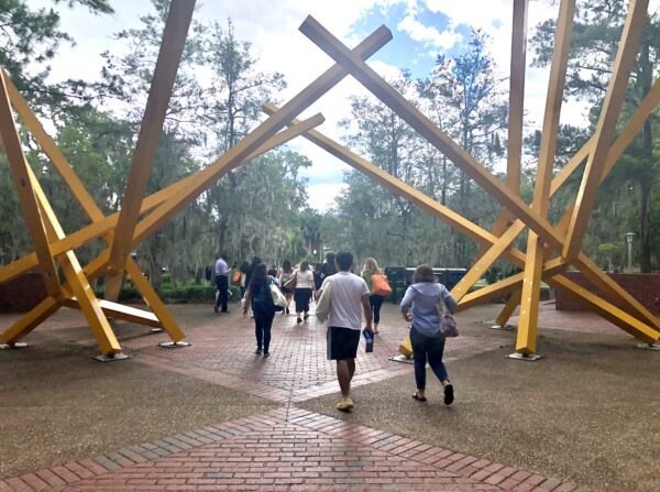 Nuevos estudiantes de la Universidad de Florida pasan por una escultura del campus conocida extraoficialmente como "Las papas fritas", el 6 de junio de 2022. (Natasha Holt/The Epoch Times)
