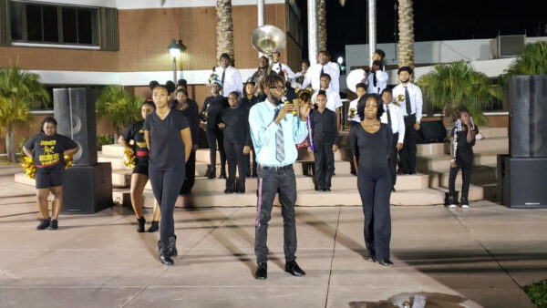 Antoine Miller, director de la banda y fundador de la Sounds of Success Community Marching Band, con algunos de sus músicos y bailarines mientras actúan en televisión para el alcalde Thomas Masters en el Ayuntamiento de Riviera Beach, Florida, en 2019. (Cortesía de Sounds of Success)