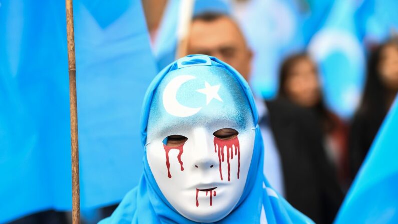 Una persona con una máscara blanca con lágrimas de sangre participa en una marcha de protesta de la etnia uigur. La marcha pide que la Unión Europea exija a China que respete los derechos humanos en la región china de Xinjiang y pida el cierre del "centro de reeducación" donde se detiene a los uigures, durante una manifestación alrededor de las instituciones de la UE, en Bruselas, el 27 de abril de 2018. (Emmanuel Dunand/AFP/Getty Images)

