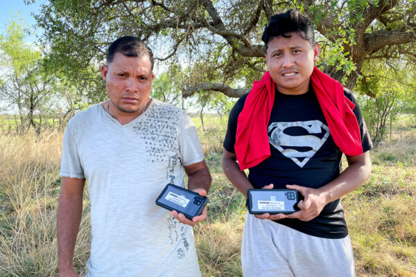 Dos nicaragüenses sostienen los teléfonos celulares que recibieron de la Patrulla Fronteriza antes de ser liberados en Estados Unidos, en el condado de Kinney, Texas, el 29 de abril de 2022. (Charlotte Cuthbertson/The Epoch Times)