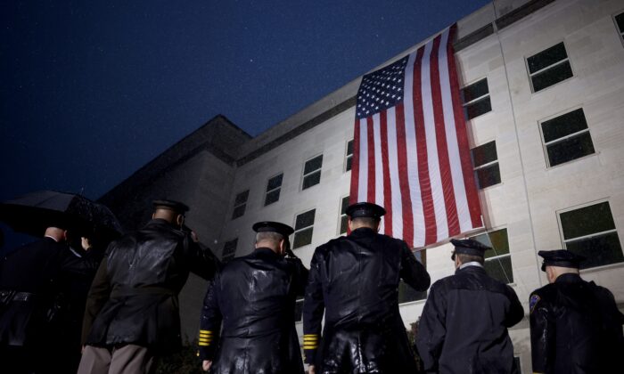 Miembros de las fuerzas armadas y socorristas saludan mientras se despliega una bandera estadounidense, en el costado del Pentágono, para conmemorar el 21° aniversario de los ataques terroristas del 11 de septiembre, en Arlington, Virginia, el 11 de septiembre de 2022. (Anna Hacedor de dinero/Getty Images)

