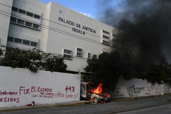 Un vehículo se incendia en la entrada del Palacio de Justicia, durante una protesta para exigir justicia por los 43 desaparecidos de Ayotzinapa, el 27 de septiembre de 2022, en Iguala, estado de Guerrero (México). EFE/ Jose Luis de la Cruz
