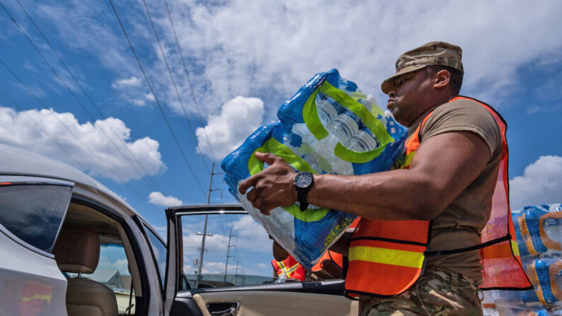 Un miembro de la Guardia Nacional coloca una caja de agua en la parte trasera de un coche en el State Fair Grounds en Jackson, Misisipi, el 2 de septiembre de 2022. (Seth Herald/AFP vía Getty Images)
