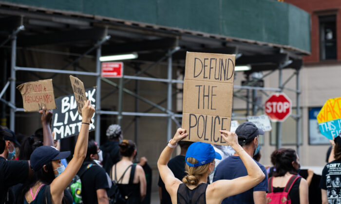 Un manifestante sostiene un cartel de “Desfinanciar a la policía” en una protesta de Black Lives Matter en Manhattan, el 13 de julio de 2020. (Chung I Ho/The Epoch Times)
