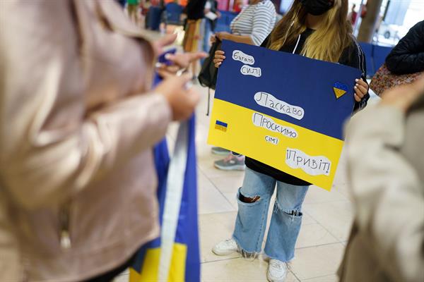 Una joven con un cartel en el que se puede leer en ucraniano "Mucha fuerza. Bienvenida familia. Hola" espera en la terminal de llegadas del aeropuerto Tenerife Norte, el 23 de abril de 2022. EFE/Ramón de la Rocha