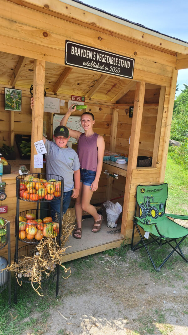 Brayden y su hermana Emma en su puesto de productos, Brayden's Vegetable Stand. (Cortesía de Kari Nadeau)