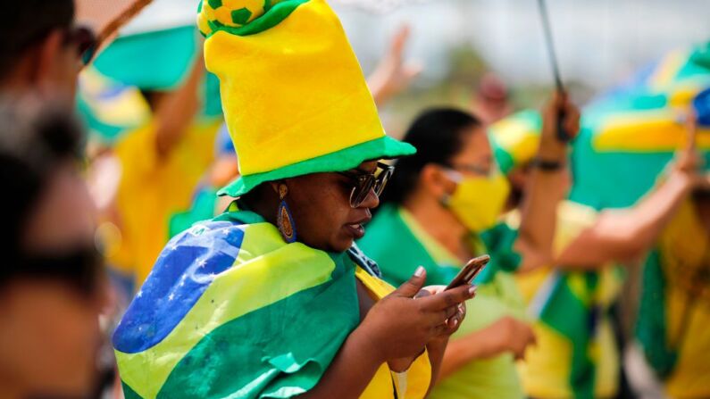 Una simpatizante del presidente brasileño Jair Bolsonaro mira su teléfono móvil durante una manifestación en Brasilia el 19 de abril de 2020. (SERGIO LIMA/AFP vía Getty Images)