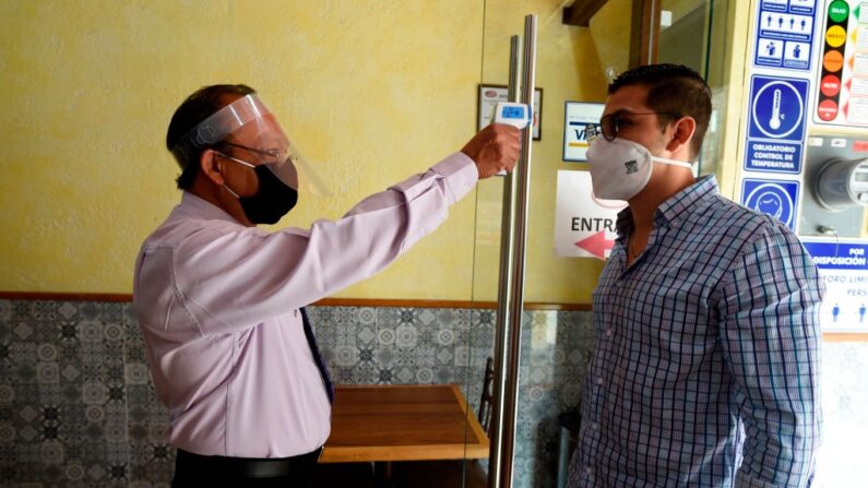 Un trabajador con máscara protectora mide la temperatura de un cliente antes de entrar en un restaurante en Ciudad de México (México), el 1 de julio de 2020 durante la pandemia de COVID-19. (Alfredo Estrella/AFP vía Getty Images)