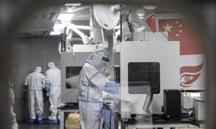 Técnicos de laboratorio que usan equipo de protección personal (EPP) trabajan en muestras para analizar el coronavirus Covid-19 en una instalación de prueba de Covid-19 en Wuhan, en la provincia central china de Hubei, el 5 de agosto de 2021. (STR/AFP a través de Getty Images)
