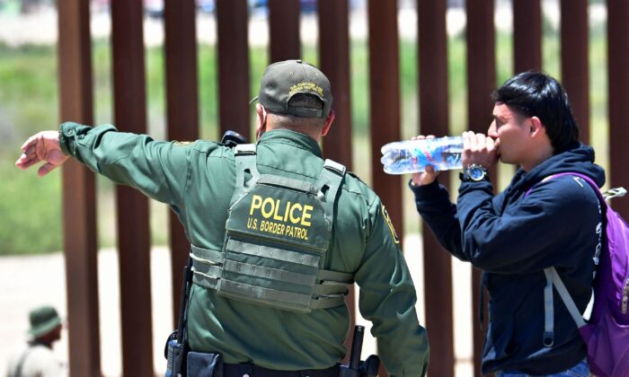 Una miembro de la patrulla Fronteriza estadounidense dirige a un extranjero ilegal después de que cruzara a Estados Unidos desde México a través de una brecha en el muro fronterizo que separa Algodones, México, de Yuma, Arizona, el 16 de mayo de 2022. (Frederic J. Brown/AFP vía Getty Images)
