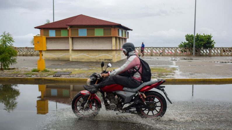 Un hombre conduce su moto por una calle inundada de agua de lluvia en la ciudad venezolana de La Guaira, ante la llegada del ciclón tropical "Bonnie" al país, el 29 de junio de 2022. (Pedro Rances Mattey/AFP vía Getty Images)