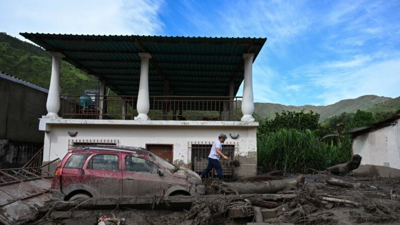 Un residente pasa por delante de un coche atascado en medio de los escombros en El Castaño, un barrio de Maracay, la capital del estado venezolano de Aragua (norte), el 18 de octubre de 2022. (Federico Parra/AFP vía Getty Images)