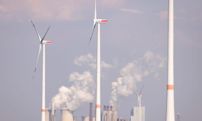 El vapor sale de las torres de refrigeración de la central eléctrica de carbón de Neurath mientras las turbinas eólicas giran sobre un campo de colza cerca de Bedburg, Alemania, el 5 de mayo de 2022. (Andreas Rentz/Getty Images)