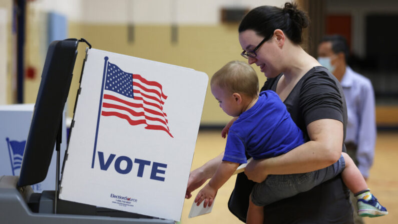 Una votante deposita su voto con su hijo en un colegio electoral de la Escuela Primaria Rose Hill durante las elecciones primarias de mitad de mandato en Alexandria, Virginia, el 21 de junio de 2022. (Alex Wong/Getty Images)
