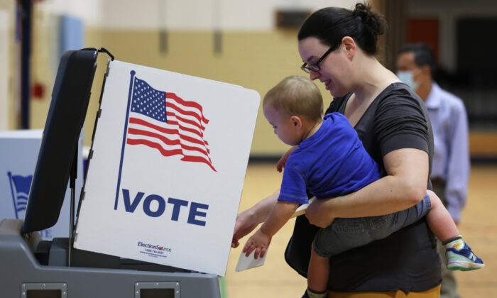 Una votante emite su voto con su hijo, en un colegio electoral de la Escuela Primaria Rose Hill durante las elecciones primarias de mitad de período, en Alexandria, Virginia, el 21 de junio de 2022. (Alex Wong/Getty Images)
